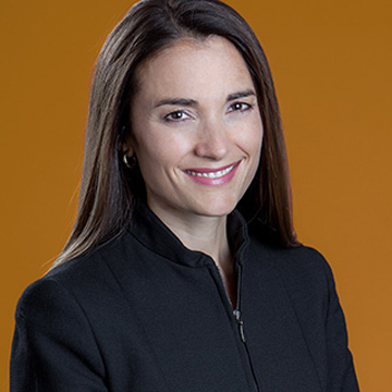 Miel Novak, a woman with long brown hair, wearing a black jacket, smiles at the camera