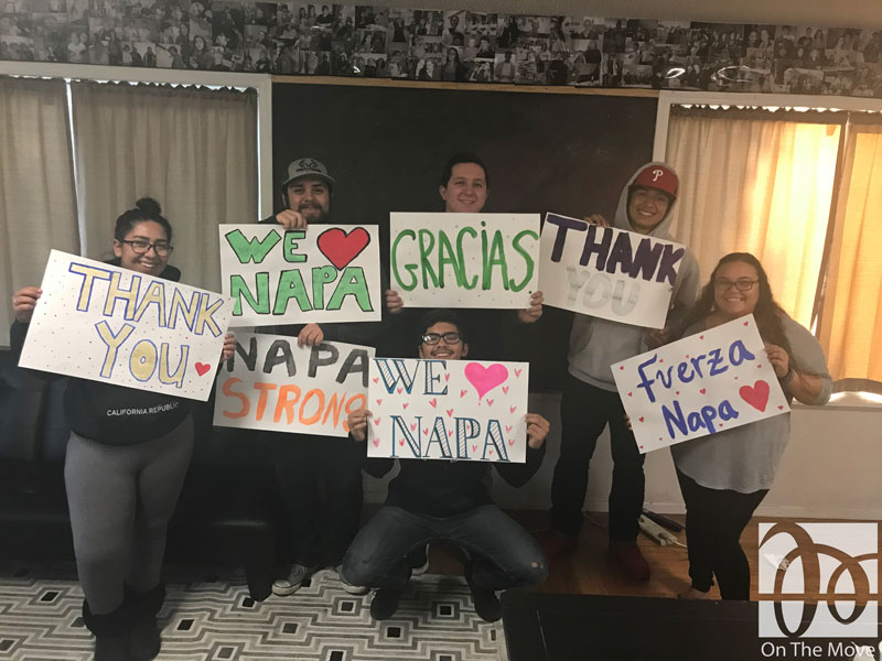 A group of people stand holding signs reading "thank you, Napa strong, we love Napa"