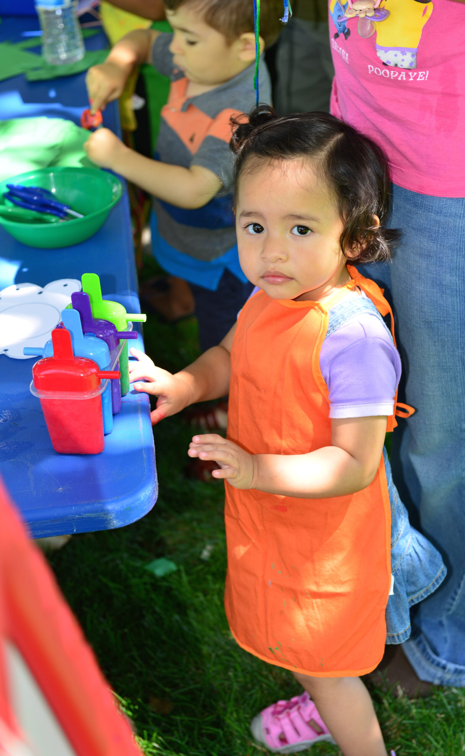 A young girl wearing an orange apron plays with the Ninos Activos playgroup