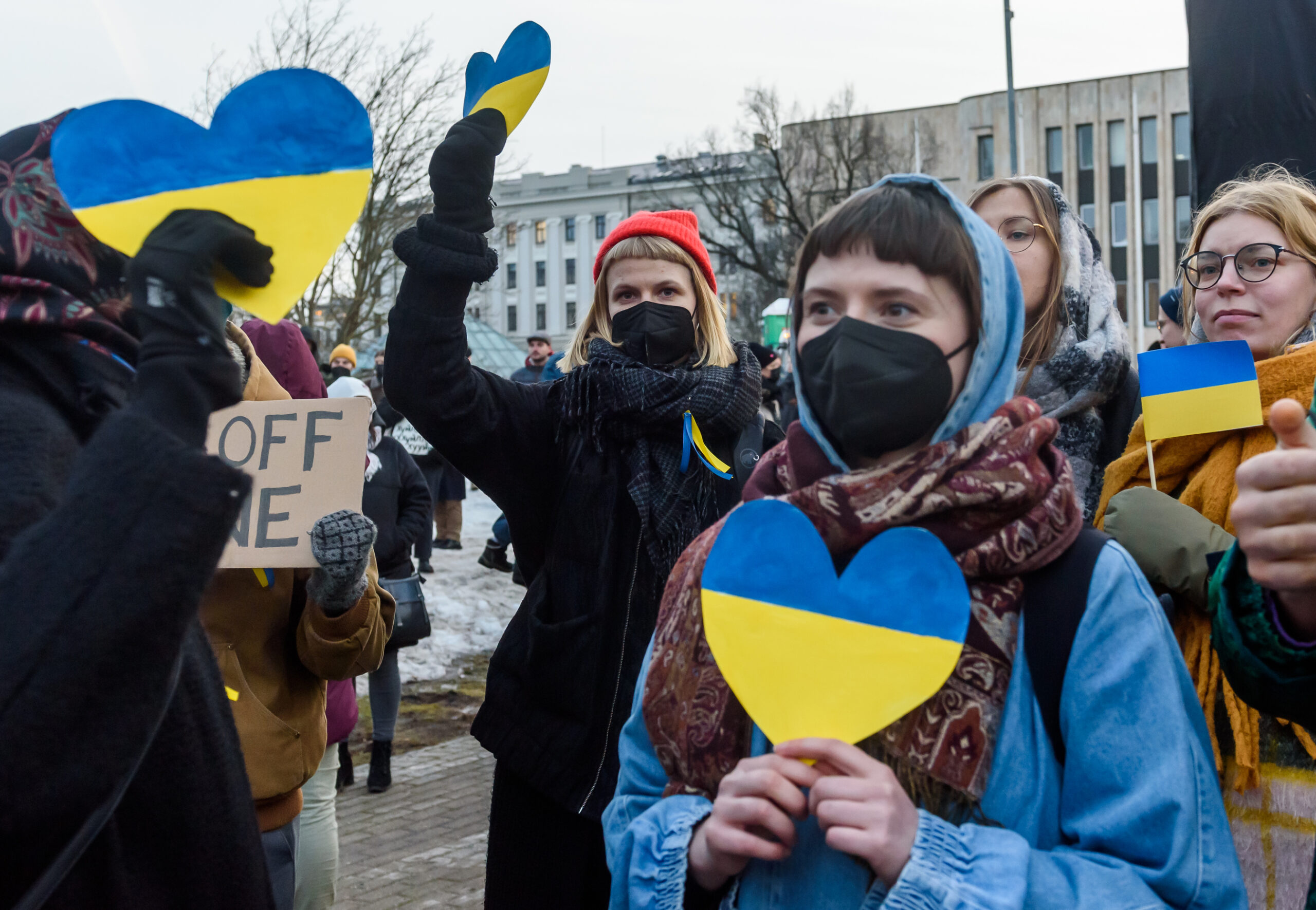 An image depicting Ukrainian People, holding hearts made out of paper, colored half blue, half yellow.