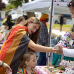Attendees visit a booth with handmade pride themed jewelry.