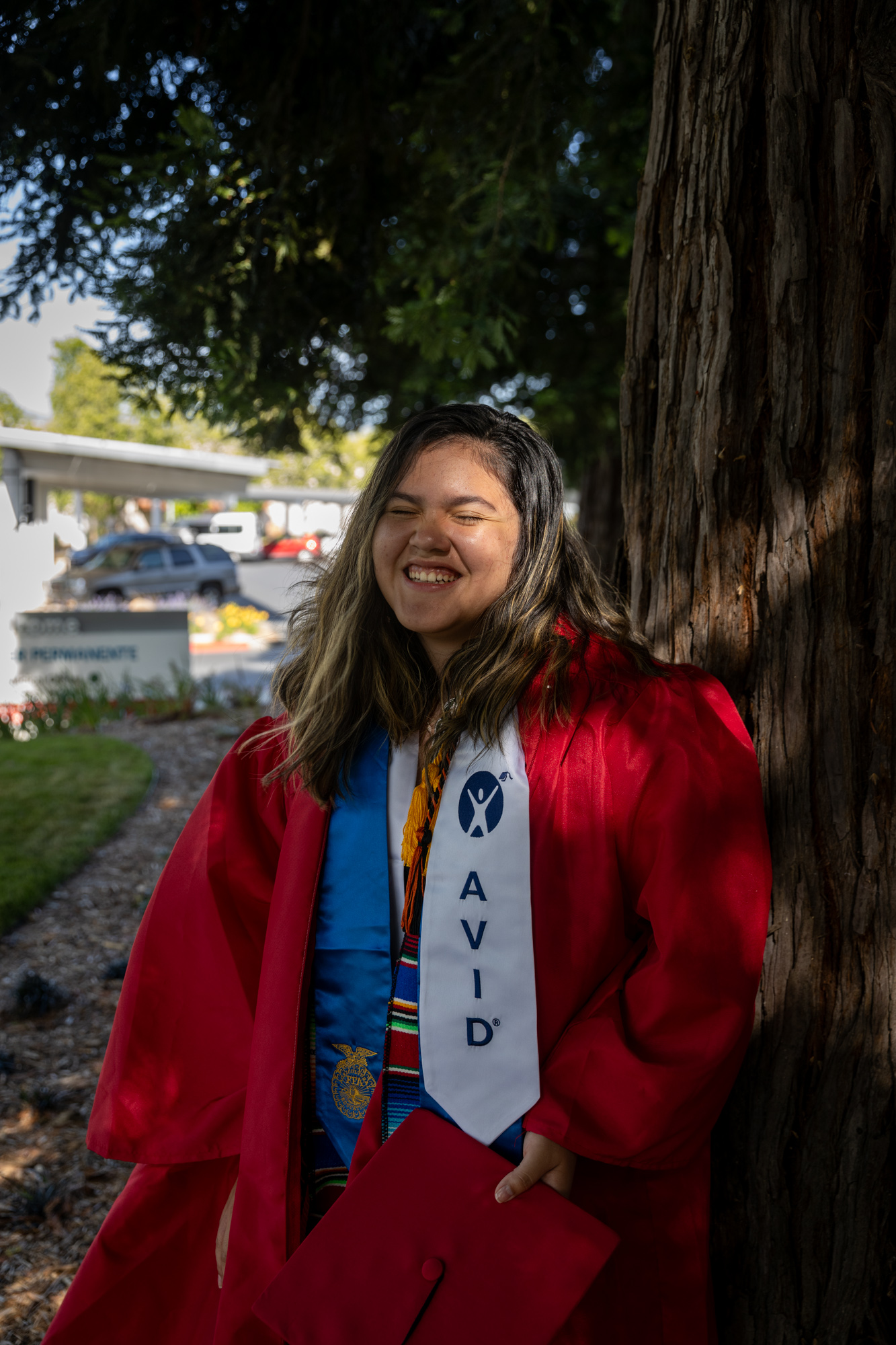 Mariela Rivera-Moreno, a young latina girl, smiles wearing her graduation gown.