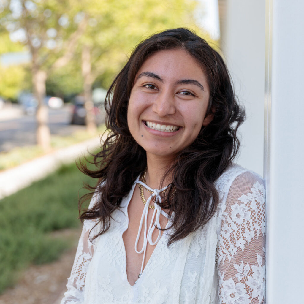 Jessica Rodriguez, Philanthropic Associate, a young Latina woman with dark brown hair, wearing a white dress, smiling.