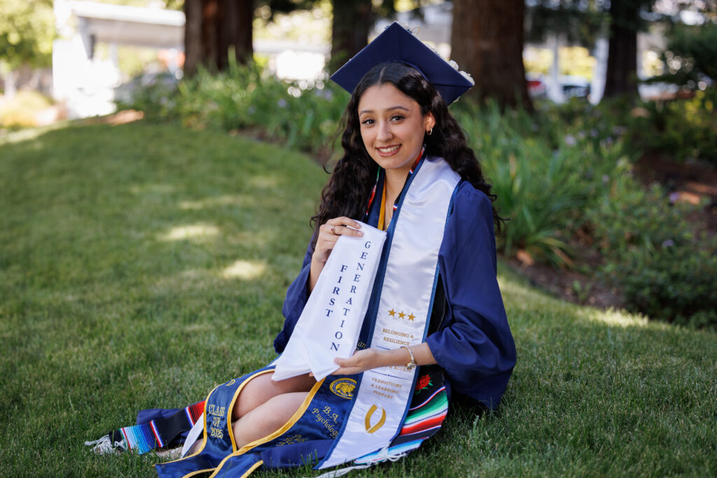 Briana Rubio sits wearing her graduation cap and gown. She is a latina woman, and she has a graduation stole reading "First Generation" Briana graduated from UC Merced this spring with a B.A. in Psychology. A Fruit of the Vine Scholarship recipient for all four years of her college journey, Briana plans to return home to Calistoga. 
